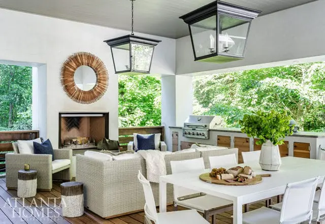 Covered patio with outdoor fireplace, sectional sofa, dining table, and built-in grill.