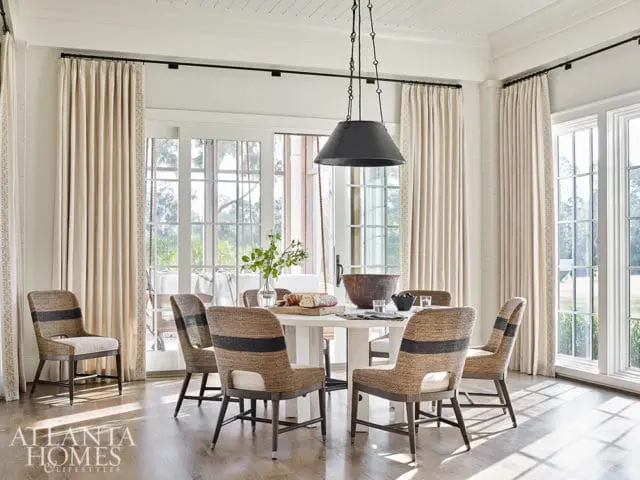 Dining room with light beige curtains, a white pedestal table, and upholstered chairs with dark horizontal stripes.