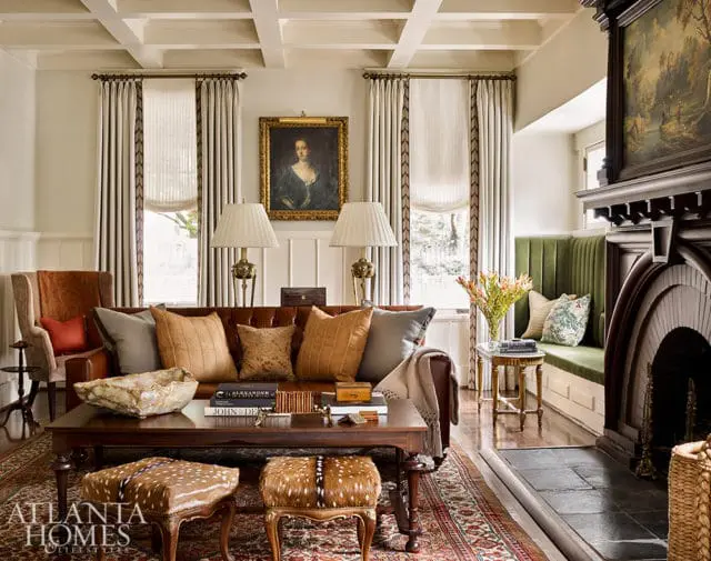 Living room with coffered ceiling, leather sofa, patterned rug, and fireplace. A green banquette is built into the wall next to the fireplace.