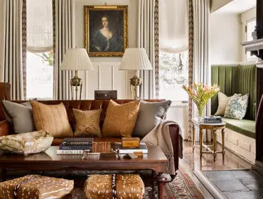 Living room with brown leather sofa, plush pillows, dark wood coffee table, fireplace, and green built-in bench seating.