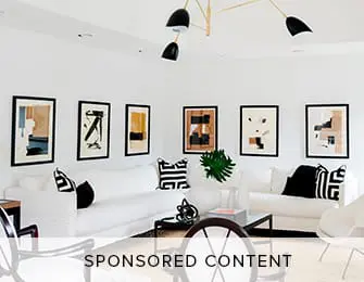 Living room with two white sofas, black and white abstract art on the wall, and a modern black chandelier.