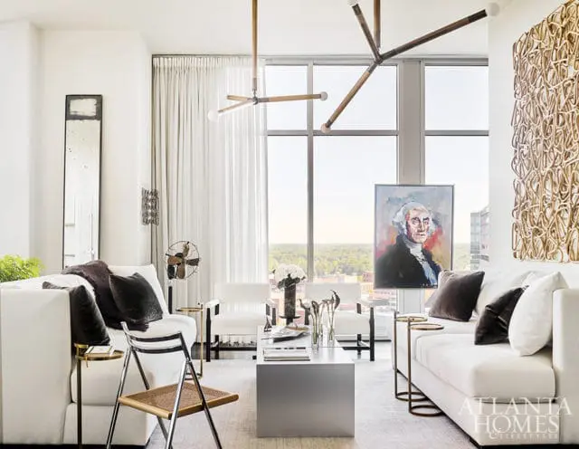 Modern living room with white sofas, abstract art, and a portrait of George Washington hanging over a cityscape view.