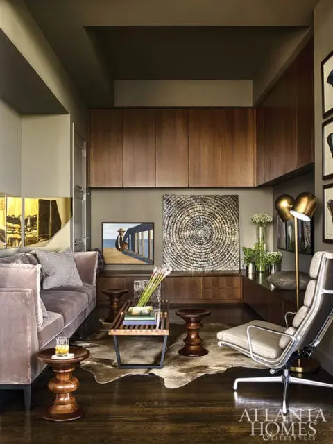 Living room with plush mauve sofa, mid-century modern lounge chair, wooden cabinetry, and abstract wall art.