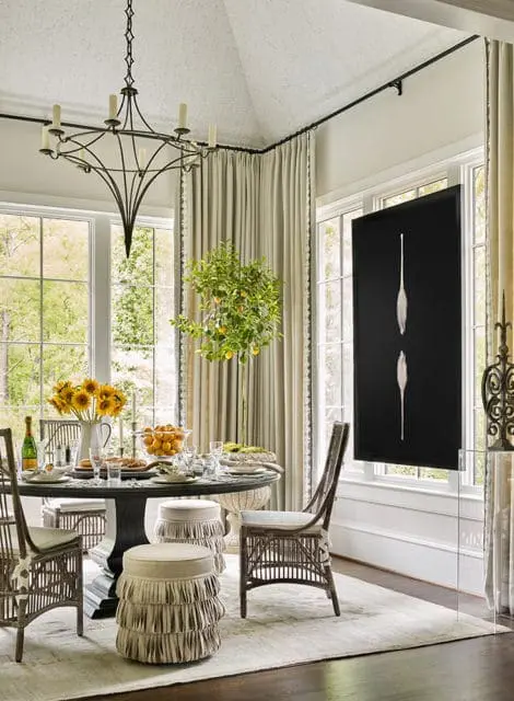 Dining room with a round table set for a meal, rattan chairs, and a large black framed artwork of two white egrets on a black background.