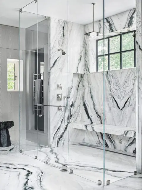 Master bathroom with a large glass-enclosed shower featuring dramatic black and white marble walls, a built-in marble bench, and a rainfall showerhead.