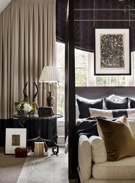 Master bedroom with a four-poster bed, dark wood accents, neutral-toned curtains, and a framed abstract artwork hanging above the bed.