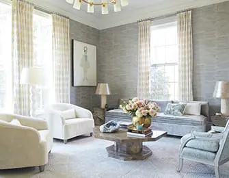 Living room with textured gray walls, cream upholstered armchairs, a light blue sofa, and a hexagonal wood coffee table with a floral centerpiece.