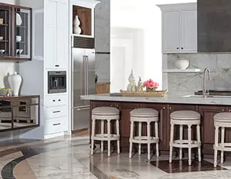 White and dark wood kitchen with marble countertops, stainless steel appliances, and four upholstered bar stools around an island.
