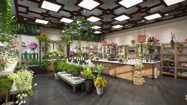 Flower shop interior with a wooden counter displaying 'FLEURS de FACES' text, shelves stocked with flowers and vases, and hanging plants from a patterned ceiling with square lights.