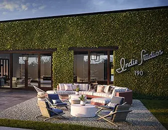 Modern building exterior covered in green vertical garden with a patio seating area featuring a curved sectional sofa and armchairs