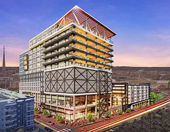 Rendering of a modern mixed-use building with multiple balconies, a prominent steel exoskeleton on the lower floors, and a sloped glass roof structure.