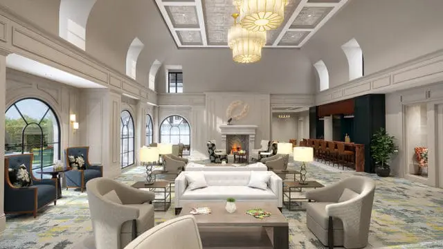 Spacious lounge with arched windows, a fireplace, a bar area, and seating arrangements including sofas and armchairs. The room features a coffered ceiling with ornate chandeliers and a patterned carpet.