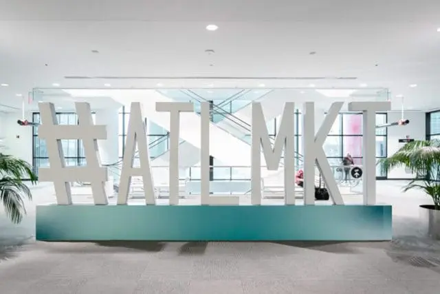 Large white 3D letters spelling #ATL MKT stand on a teal base in a modern lobby with escalators and plants in the background.