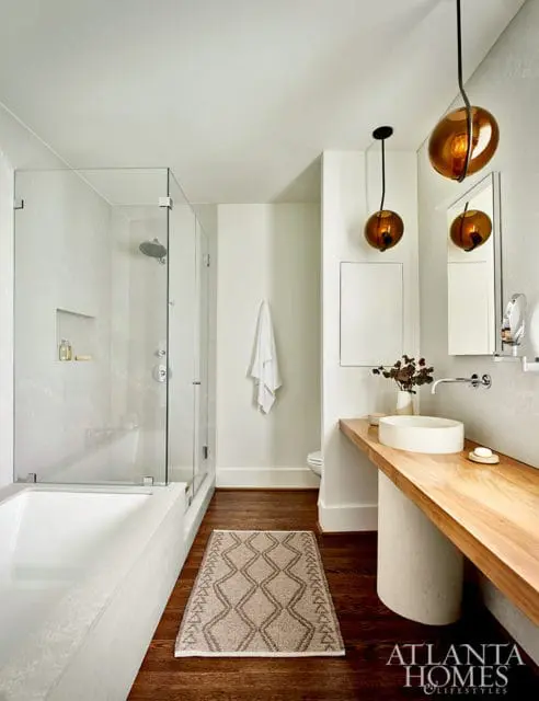 Modern bathroom with glass-enclosed shower and tub, floating wood vanity with vessel sink, and amber pendant lights.