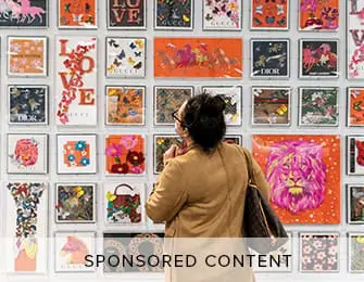 Woman looking at a wall display of framed artwork featuring butterflies, horses, flowers, and brand logos like Dior and Gucci.
