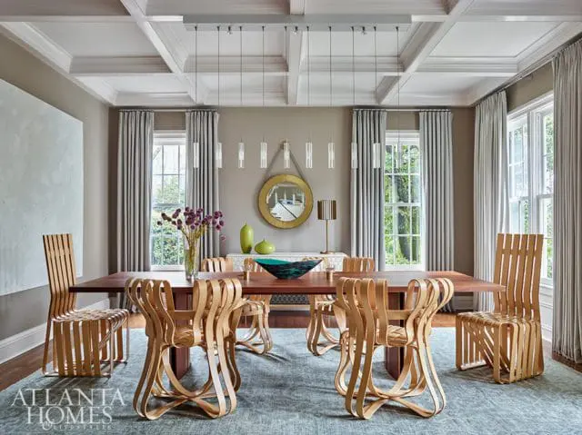 Dining room with a dark wood table and unique wood-slat chairs, a coffered ceiling with modern pendant lights, and large windows with grey curtains.