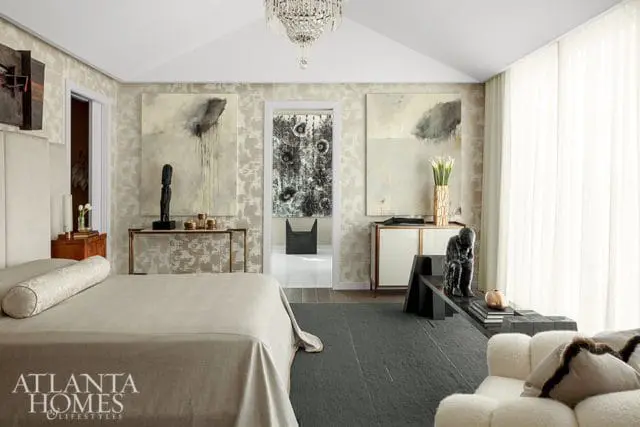 Master bedroom with textured wallpaper, abstract art, a large bed with neutral bedding, and a crystal chandelier.