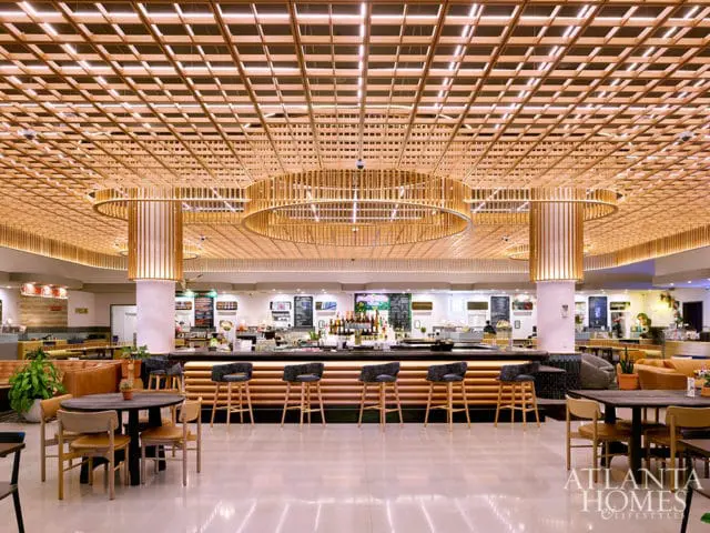 Modern bar area with a wood slat ceiling, circular pendant lights, and a long bar with upholstered stools.
