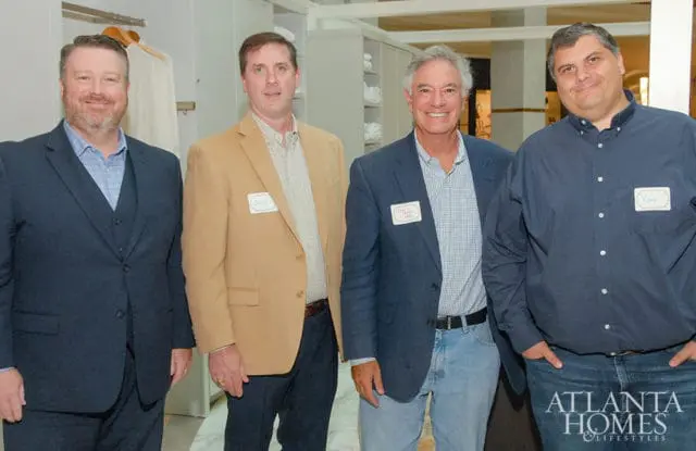 Four men stand together, each wearing a name tag. The man on the far right has the Atlanta Homes & Lifestyles logo on his jeans.