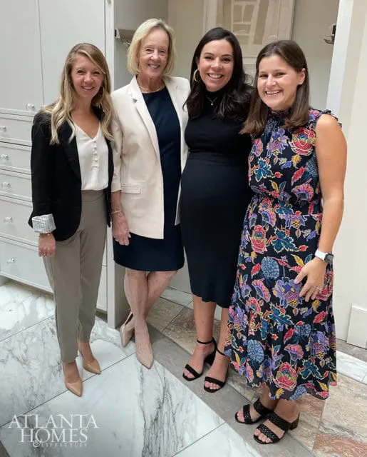 Four women pose for a photo in front of a wall of drawers and marble flooring. The Atlanta Homes & Lifestyles logo is visible in the bottom left corner.