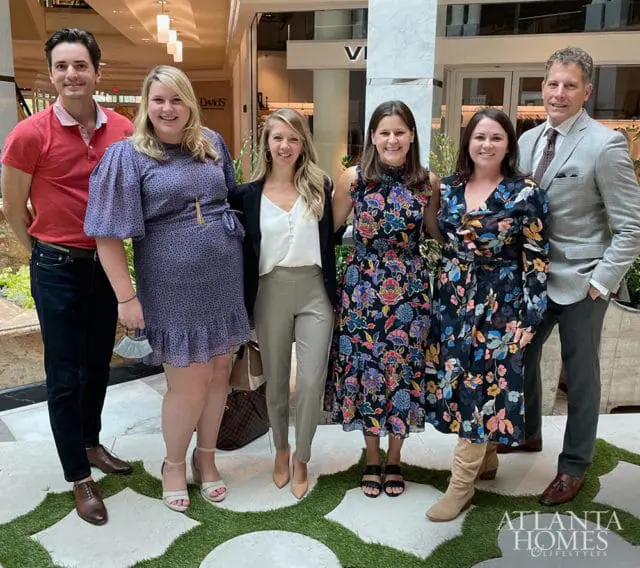 Six people pose for a photo in a well-lit indoor space with a logo for Atlanta Homes & Lifestyles visible in the lower right corner.