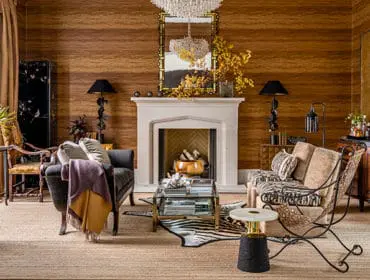 Living room with wood-paneled walls, stone fireplace, and eclectic furniture.