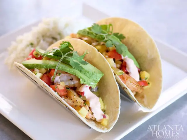 Two shrimp tacos with avocado, salsa, and cilantro, served with rice