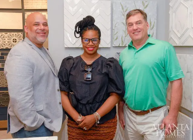 Three people smiling in front of tile samples. Atlanta Homes & Lifestyles logo visible.