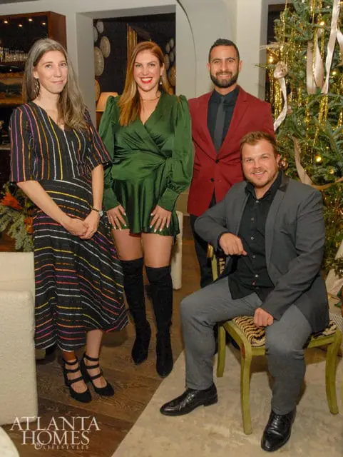 Four people posing in front of a Christmas tree.