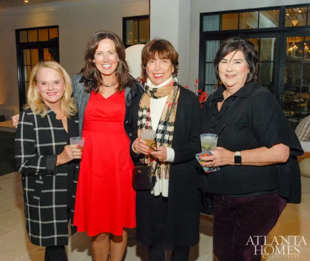Four women holding drinks at an event.