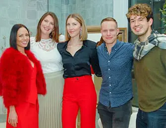 Five people posing for a photo, three women and two men, in red and white attire.