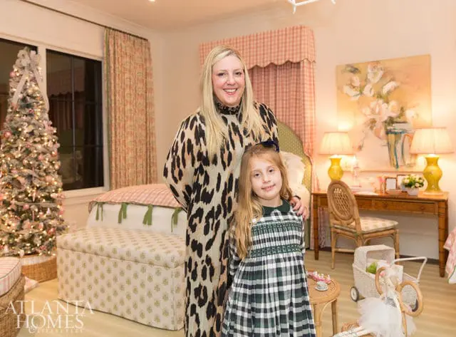 Woman in leopard print dress and girl in plaid dress in a room with a Christmas tree
