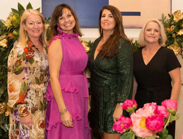Four women pose in festive attire, with floral arrangements and gold accents.
