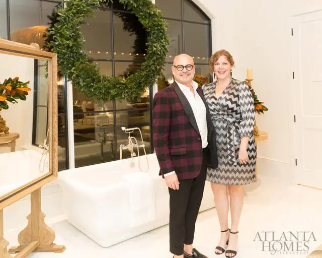 Man in plaid jacket and woman in patterned dress stand by a freestanding bathtub with a large