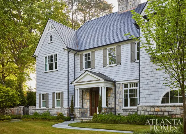 Gray shingle-clad house with stone foundation, white trim, and gray shutters.
