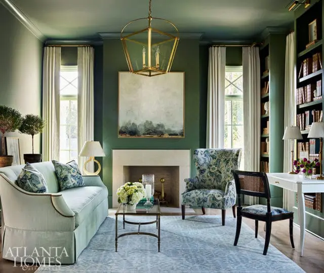 Green living room with fireplace, patterned armchair, and light blue sofa.