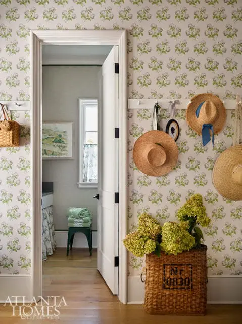 Hallway with floral wallpaper, straw hats, and a wicker basket of hydrangeas