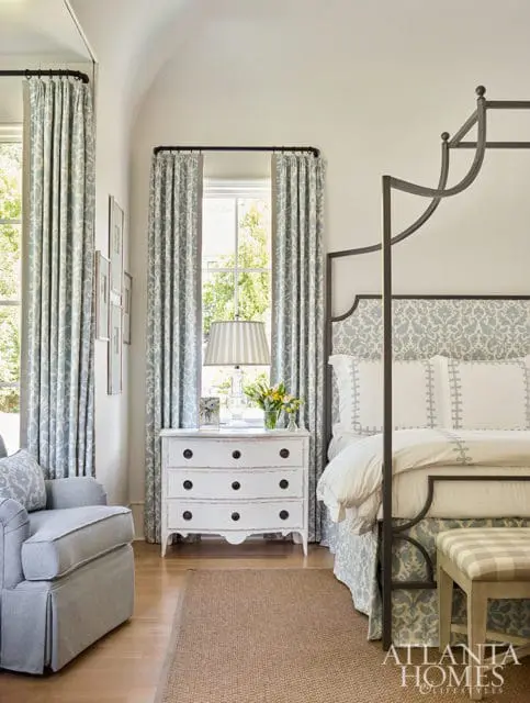 Bedroom with a four-poster bed, patterned curtains, and a white dresser.