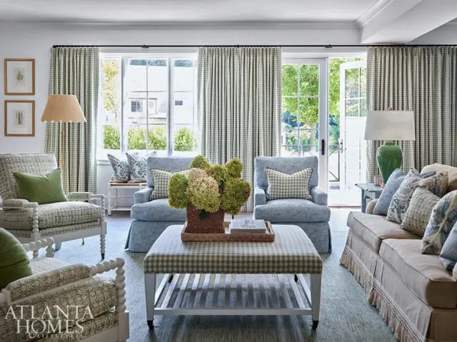 Living room with blue chairs, sofa, and plaid ottoman. Green hydrangeas in basket.