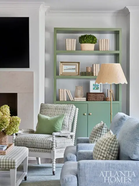 Living room with green built-in shelves, patterned armchair, and blue sofas.