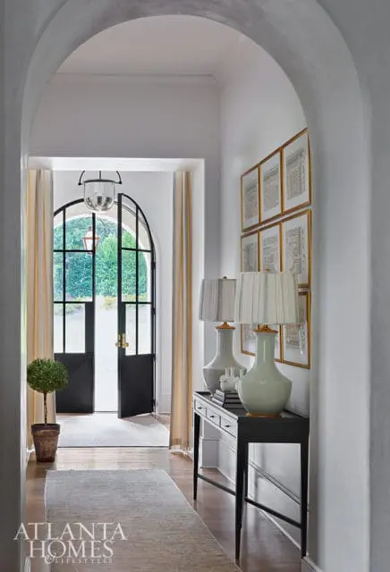 Hallway with arched doorway, console table with lamps, and framed art.