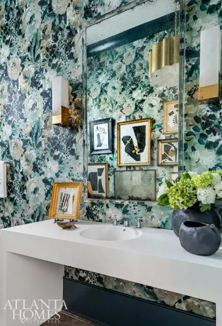 Powder room with floral wallpaper, white vanity, oval sink, and gallery wall of framed art.