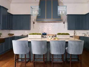 Kitchen with dark blue cabinets, marble island, and light blue bar stools.