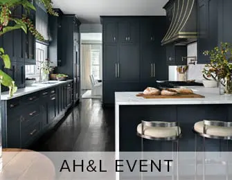 Dark blue kitchen with white marble countertops and island, brass hardware, and stainless steel