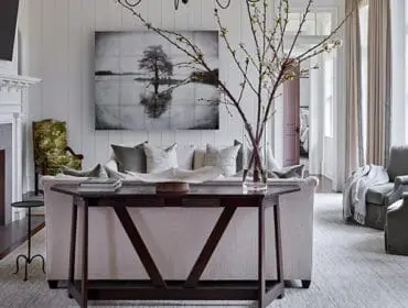 Living room with fireplace, sofa, armchairs, and artwork of a tree in water.
