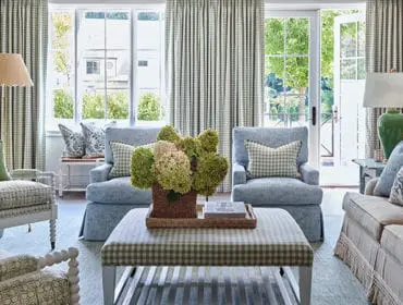 Living room with blue upholstered chairs, a beige sofa, and green and white gingham curtains.