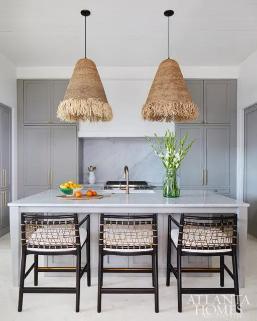 Gray kitchen with island, woven bar stools, and large jute pendant lights.