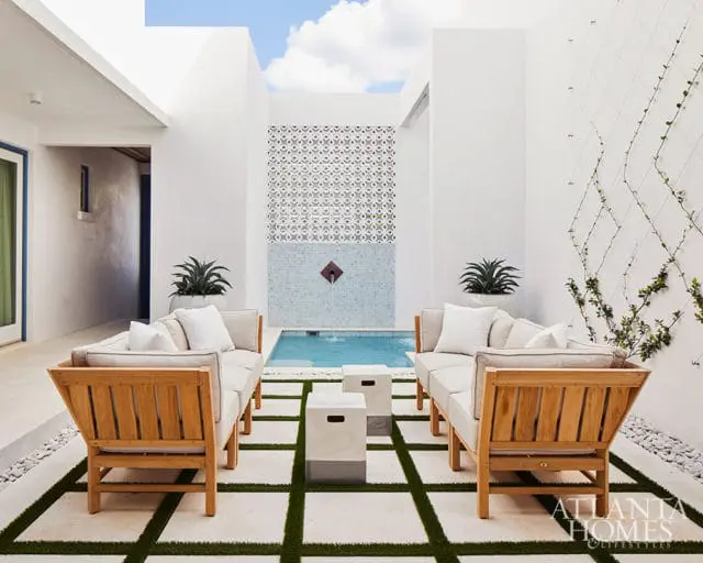 Courtyard with two teak sofas, a small pool, and a patterned tile wall.