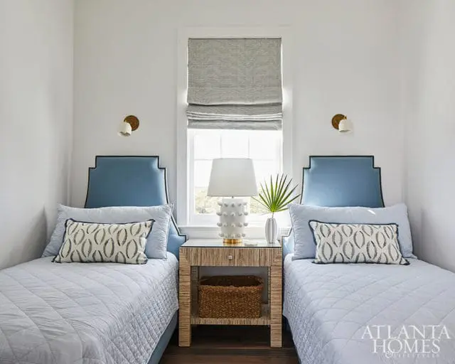 Bedroom with two twin beds, blue upholstered headboards, and patterned accent pillows.