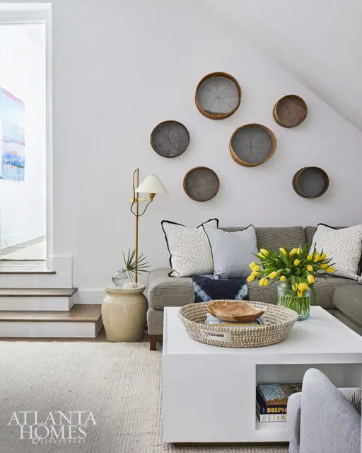 Living room with gray sofa, white coffee table, and wall decor of vintage sieves.